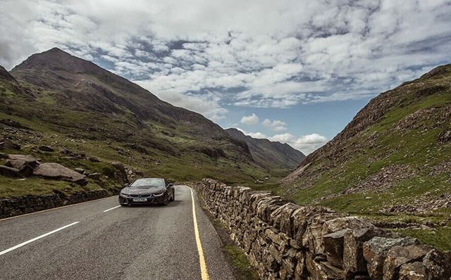 Black car driving through the mountains on a cloudy day